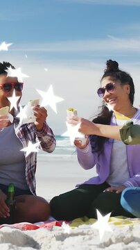 Friends sitting on blanket beach third reaching in toasting wraps while stars drifting for ads