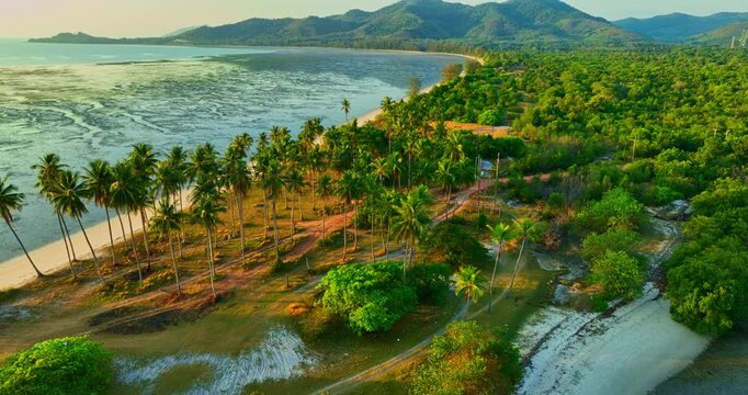 A mesmerizing aerial view of Laem Haad sandbar reveals dragon scale patterns beneath shallow waters. Tourists stroll along the white strip linking two island, forming a surreal tropical scene.