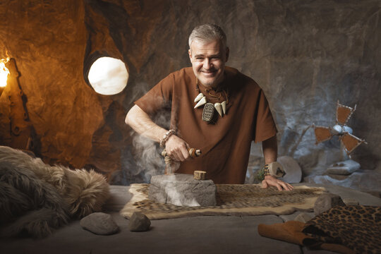 Happy confident caveman ironing his clothes and smiling at the camera