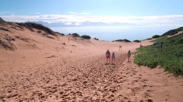Mom and kids hike down big sand dune on Robberg Hiking Trail in Plettenberg Bay