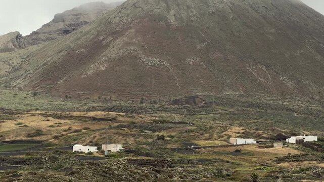 Detalle del paisaje de Lanzarote con volc&aacute;n, cultivos y peque&ntilde;o pueblo al fondo