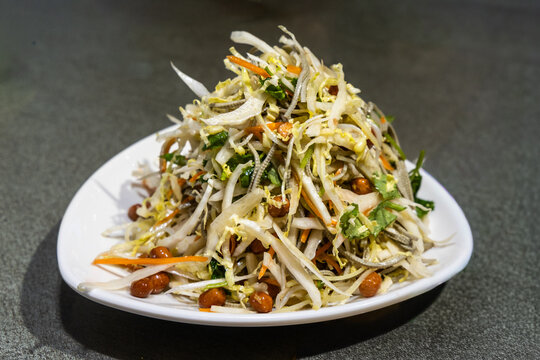 Serving of delicious Chinese specialty cold salad with cabbage and groundnuts as appetizer.