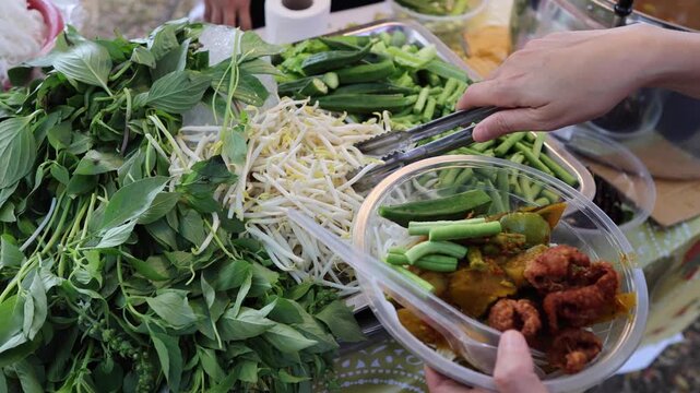 Serving fresh Vietnamese herbs and noodles with curry dish in a plastic container.