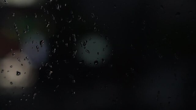 Raindrops on a car window with blurred background of street traffic lights