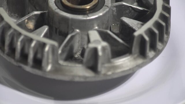Close-up of a rotating aluminum motorcycle CVT movable drive face on a white background. Showing the roller weight slots, center bushing, and metallic engineering details. Ideal for scooter transmissi