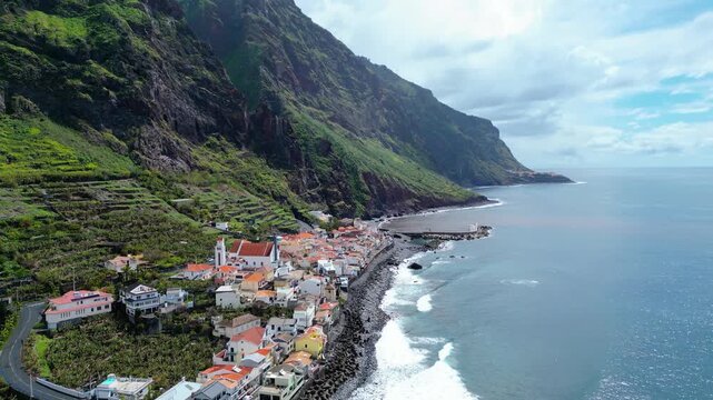 Aerial view of Paul do Mar, Madeira, where a charming village nestles between lush, terraced mountains and the Atlantic Ocean.