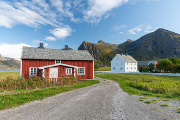 Obraz premium Red Nordic house with mountain backdrop and rural village in the Lofoten Islands, Norway