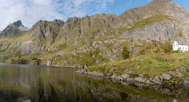 White house by fjord with dramatic mountain backdrop in the Lofoten Islands, Norway