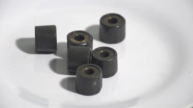 Six black scooter CVT roller weights with brass cores rotating on a white background. Perfect for automatic motorcycle transmission tuning, variable speed variator maintenance, and mechanical spare pa