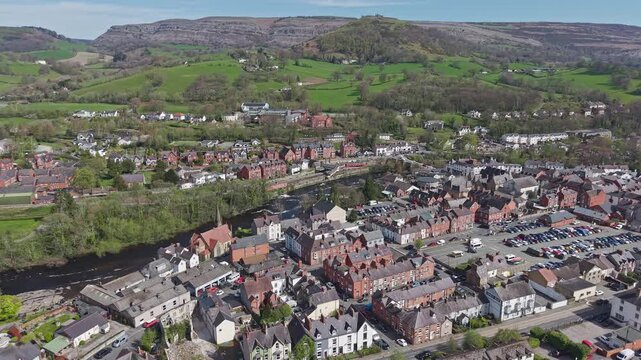 Aerial view shows the town centre of Llangollen and the flowing River Dee with a backdrop of lush green hills in the North Wales countryside