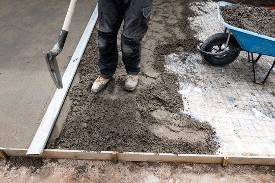 Worker leveling fresh concrete for slab foundation