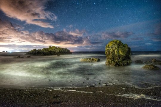 Dunure harbour pebble and rock shore with sunset and green moss near ayr on summer night.