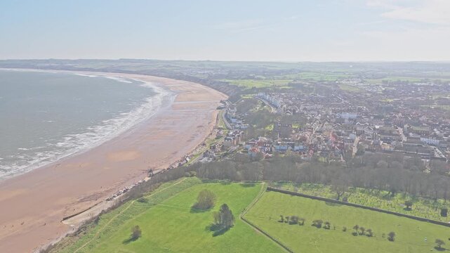 Filey Bay and town of Filey North Yorkshire England with Ravine Road seafront, wide sandy beach and North Sea coastline transitioning into farmland and urban area, drone forward glide shot