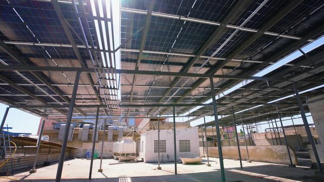 Underside of rooftop solar panels with metal framework above HVAC equipment, showing urban renewable energy infrastructure.