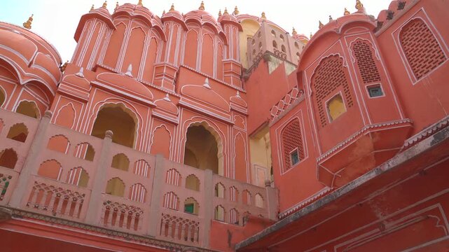 A static low-angle shot of the inner courtyard facade of the Hawa Mahal (Palace of Winds), featuring its iconic pink sandstone, white lime borders, and intricate honeycomb windows.