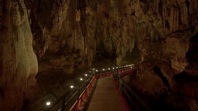 Camera pushes forward and looks up at a stalactite before tilting down to show the walkway again.