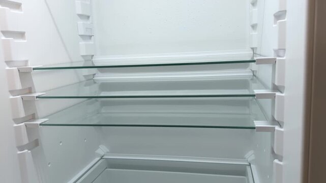 Inside view of an empty refrigerator with glass shelves