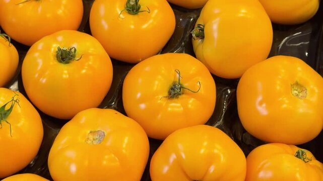 Group of fresh yellow tomatoes arranged in a container