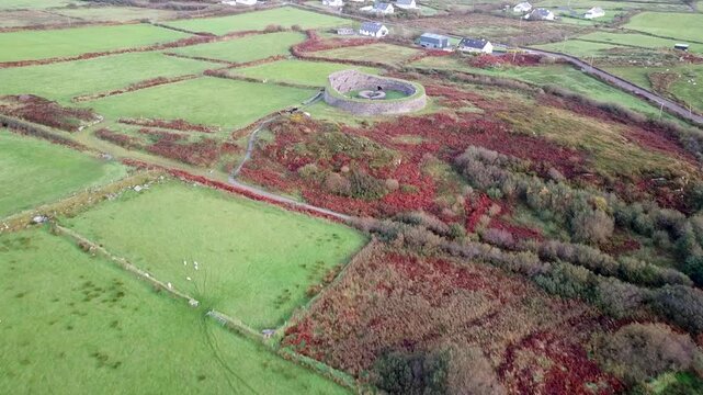 Drone shot approaching a historic Cahergal Ringfort or stone cashel surrounded by traditional patchwork farmland and rural homes
