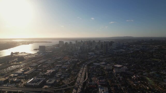 Drone pulling back at 6PM facing downtown San Diego capturing a wide view of the skyline and city layout.