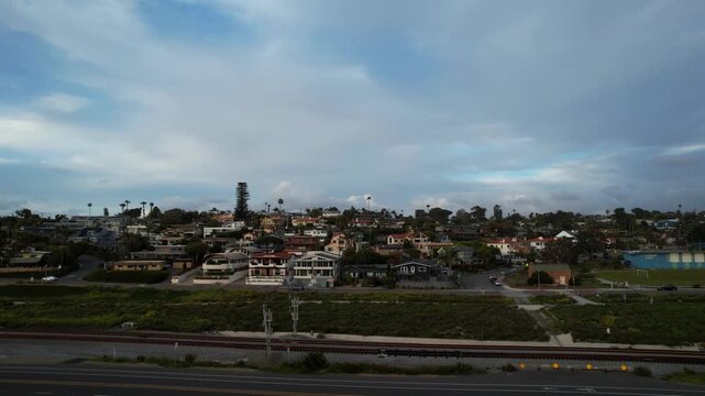 Drone flying forward at 9AM toward coastal homes in Encinitas California capturing residential neighborhood and ocean proximity.