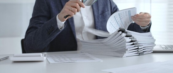 Fototapeta premium Professional reviewing corporate financial statements with magnifying glass, auditing reports, taxes and expense details. Audit and taxes