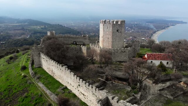 A medieval fortress with a prominent tower and stone walls overlooking a coastal landscape. Ideal for historical documentaries or travel features.