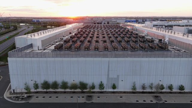 Aerial drone view of modern data center facility in Ashburn, Virginia at sunset with rows of cooling units on rooftop, symbolizing cloud computing, AI infrastructure and digital technology growth.