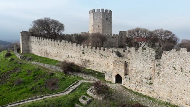 A historic fort with a stone wall and central tower on a green hillside. Suitable for historical documentaries or travel content.