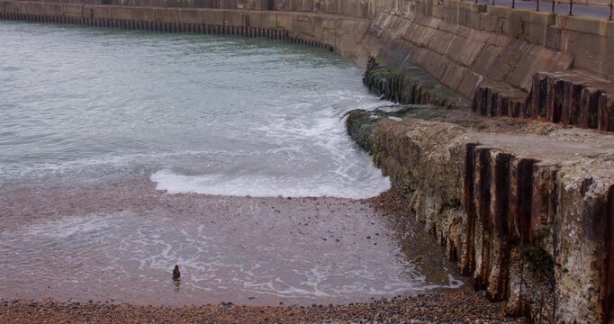 Extra Wide shot of waves lapping over old concrete next to Shoreham harbour