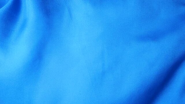 Natural blue silk fabric fluttering in the wind. Abstract flowing waves of bright blue textile. Smooth texture of real silk moving in the air. Soft drapery of natural fabric.
