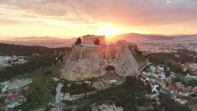 Beautiful aerial view of the acropolis of athens with the iconic parthenon temple, showing the sun setting directly behind the ancient structure creating a spectacular golden silhouette