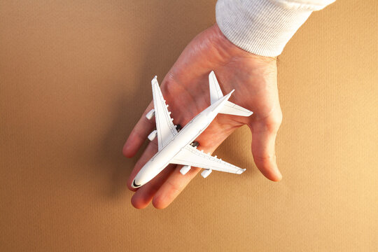 Model of a passenger plane in the palm of your hand on a brown background