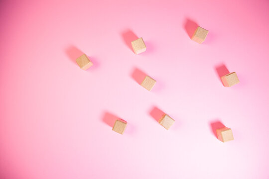 Wooden cubes of different sizes on a pink background. Flat lay.