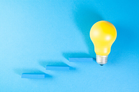 Yellow light bulb on blue background. Concept of creative idea and innovation.