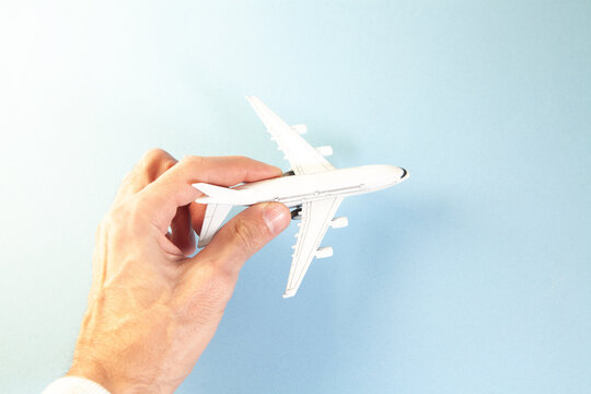 Airplane model in hand on a blue background. Travel concept.
