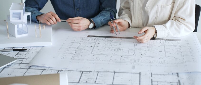 Architects working together, developing a building design by assembling a scale model and reviewing detailed blueprints, symbolizing teamwork, planning, and architectural creation