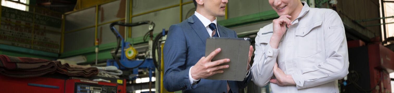 Two people: a factory worker holding a tablet and a sales representative meeting with representatives from a credit union or similar institution. without face banner