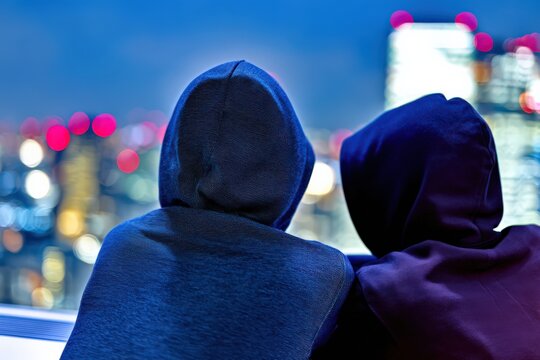 夜景を眺めるフードを被った二人