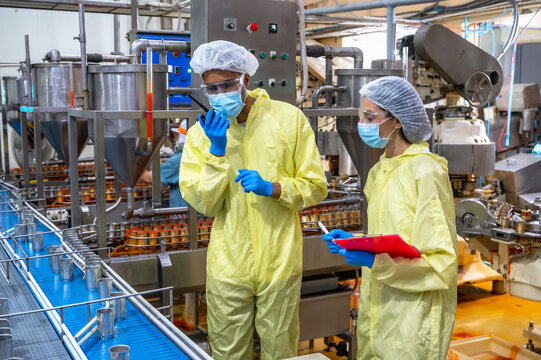 Male and female food factory inspector team inspecting fresh fish working in seafood can industry on conveyor belt
