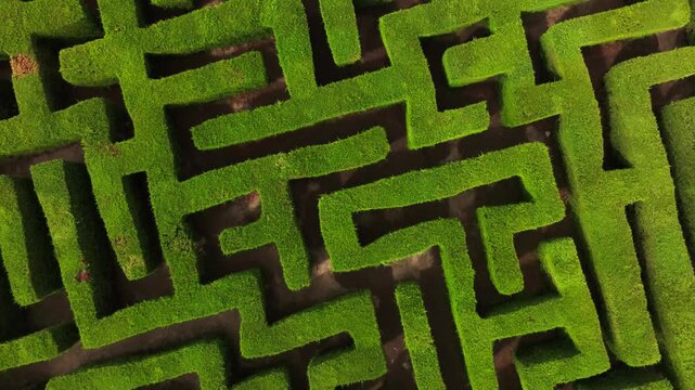 Drone flying over a square garden labyrinth, overhead geometric landscape.