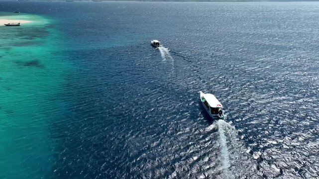 Boats cruising on vast blue ocean, distant view of Mount Merapi, Ijen