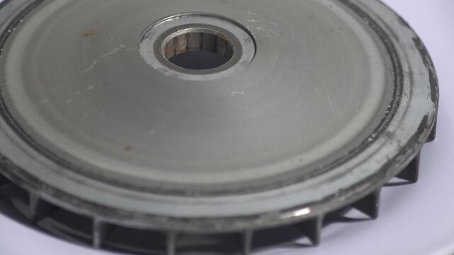 Close up of a used motorcycle CVT variator pulley or primary sliding sheath on a white background. Detailed view of metallic transmission component showing wear and tear from engine friction. Professi