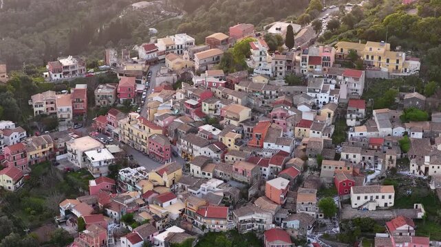 Aerial view of colorful houses in the hilltop village of Pelekas, Corfu, Greece. Drone flight over beautiful Mediterranean traditional architecture.