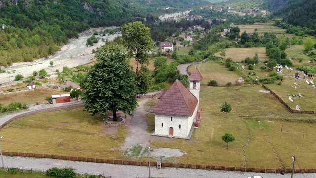 Aerial view of the stone church of Theth, a famous landmark located in a green valley in the heart of the Albanian Alps national park
