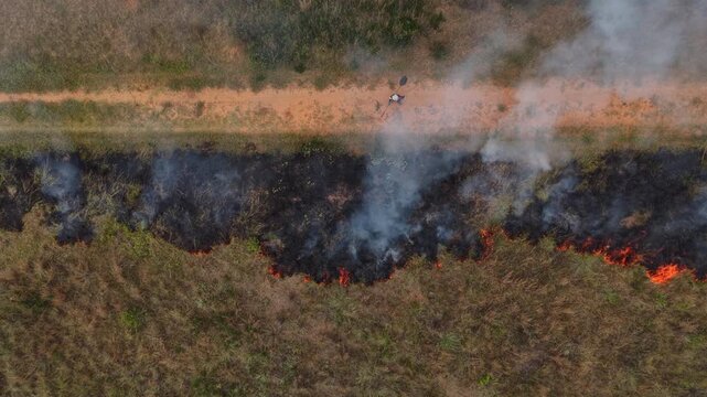 Firefighter patrols controlled burn edge to prevent spread on farmland