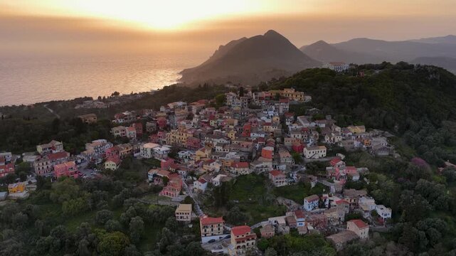 Close Aerial View of Pelekas Village Corfu at Sunset. Traditional Colorful Architecture of Greek Mountain Village with Sun Over the Ionian Sea