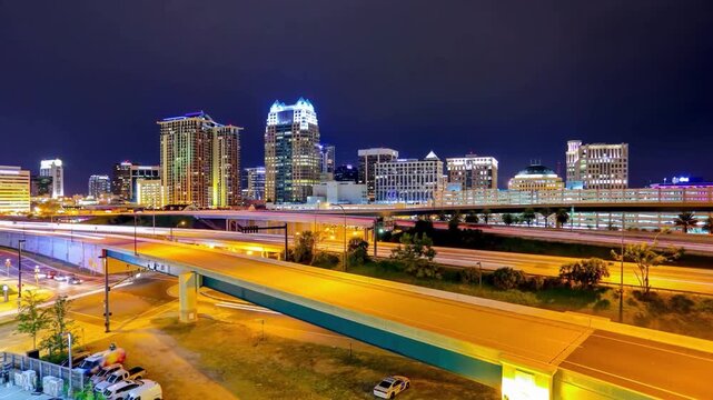 Dynamic nighttime timelapse of the illuminated Orlando skyline featuring light trails from busy traffic on Interstate 4.
