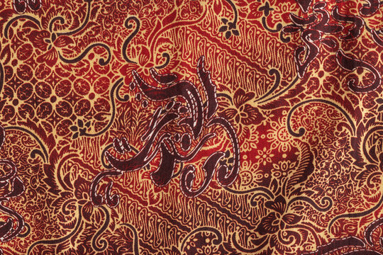 Traditional Indonesian Batik Pattern with Floral and Parang Ornaments in Red and Brown Earth Tones.
