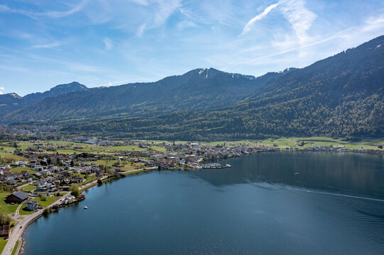 Aerial panoramic view of Lake Zug shoreline - Swiss lakeside town, green fields and alpine foothills